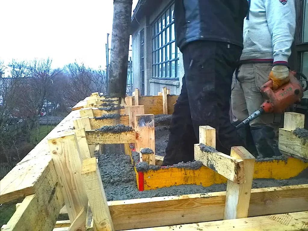 Smiður steypir ytri brún svalanna í mót.