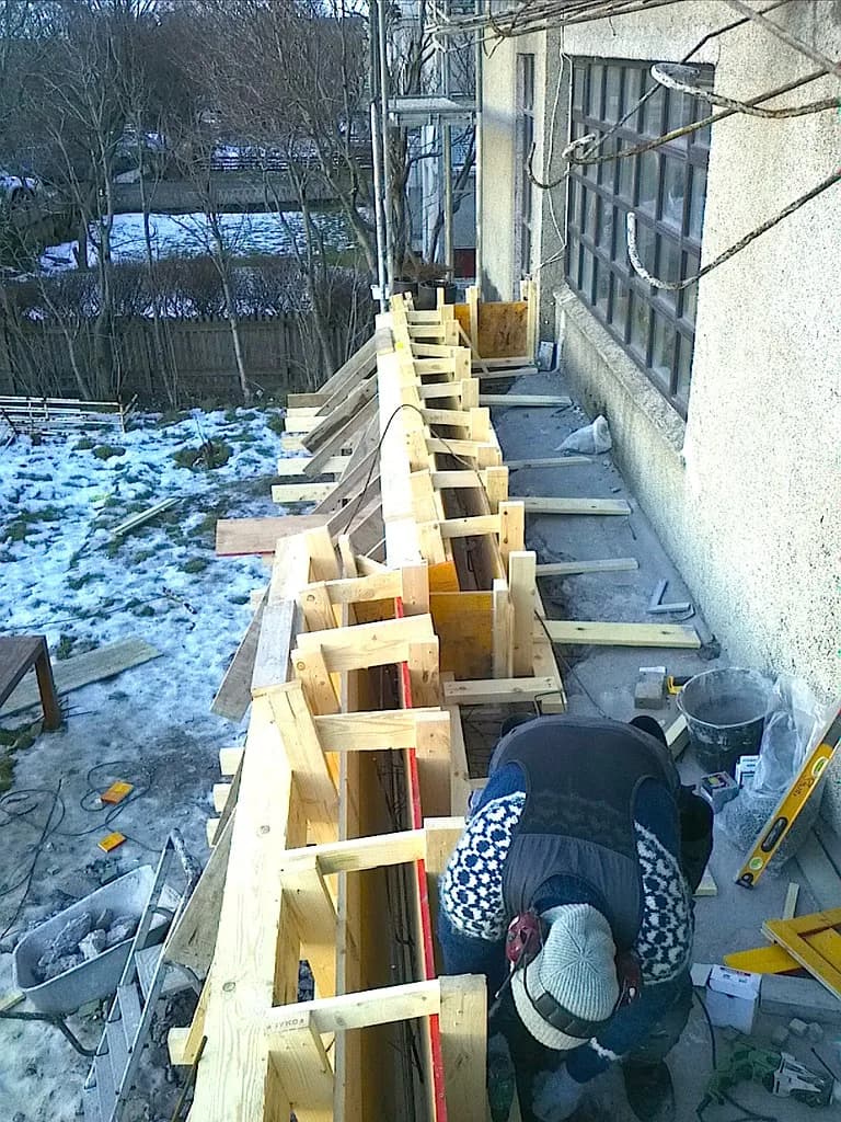 Smiður vinnur við ytri brún svalamóta.