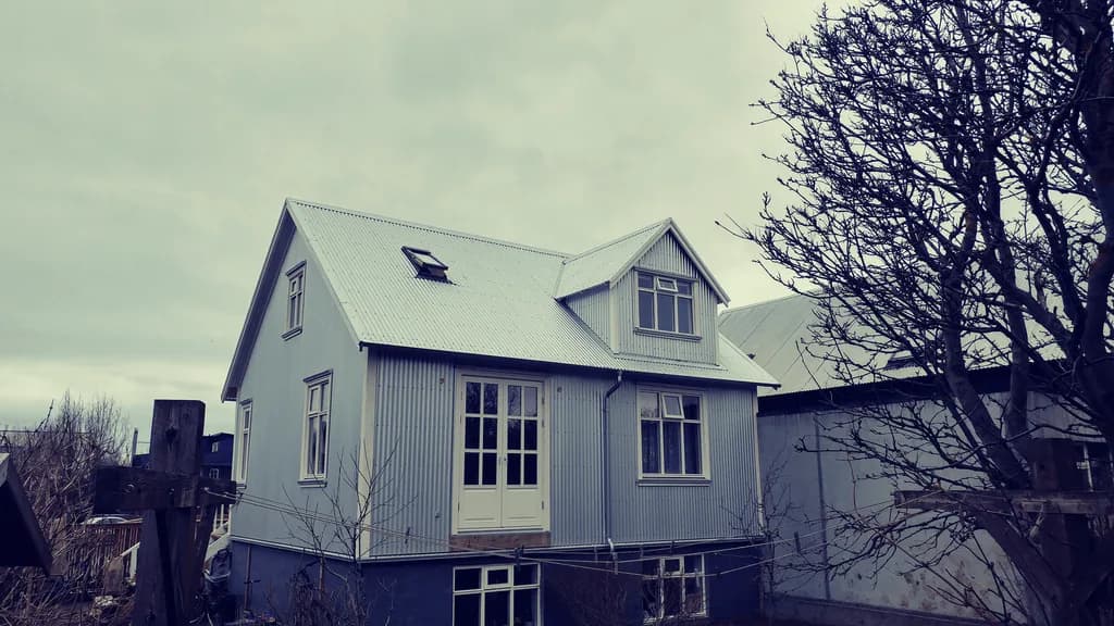 Timburhús með ljósri útveggsklæðningu, þakglugga og gaflkvisti.