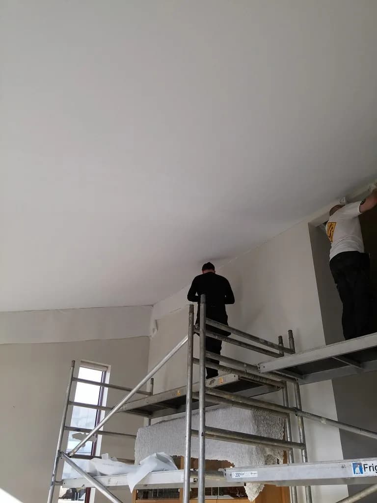 Smiðir setja hvítan loftadúk á hallandi loft.