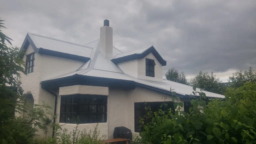 Ljós þakklæðning við skorstein og kvist á hvítu húsi.