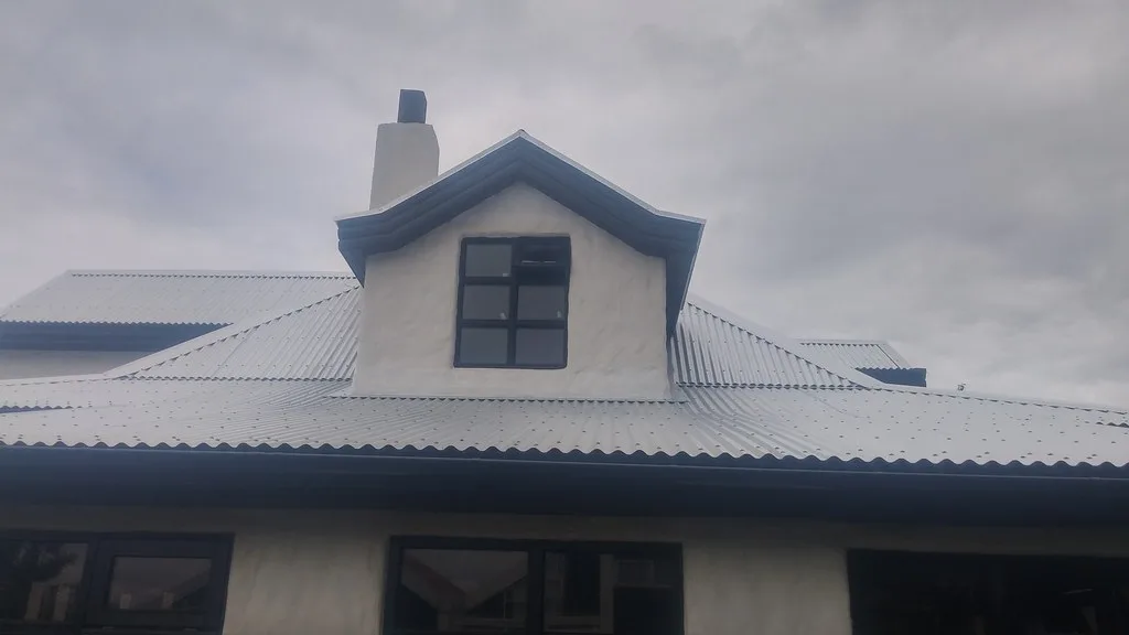 Gluggakvistur og hvítur skorsteinn á ljósu málmþaki.
