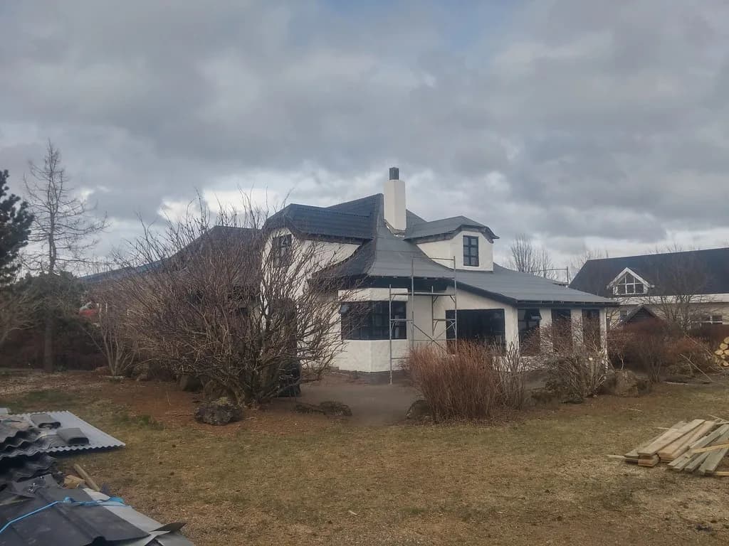Einbýlishús með kvistum og skorsteini, séð úr garði.