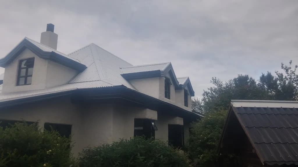 Einbýlishús með nýju ljósu málmþaki og kvistum.