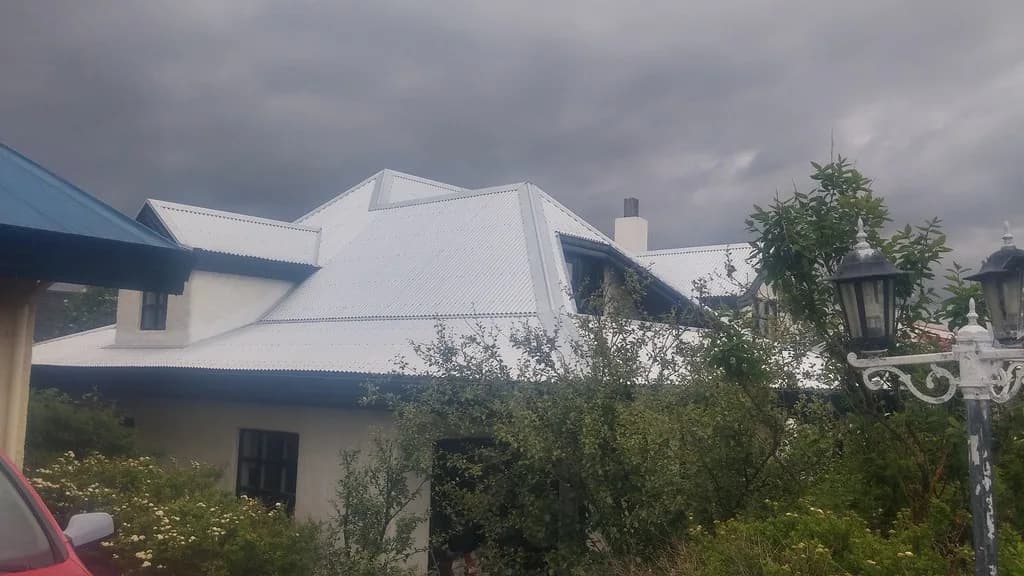 Einbýlishús með nýju ljósu báruþaki og kvistum.
