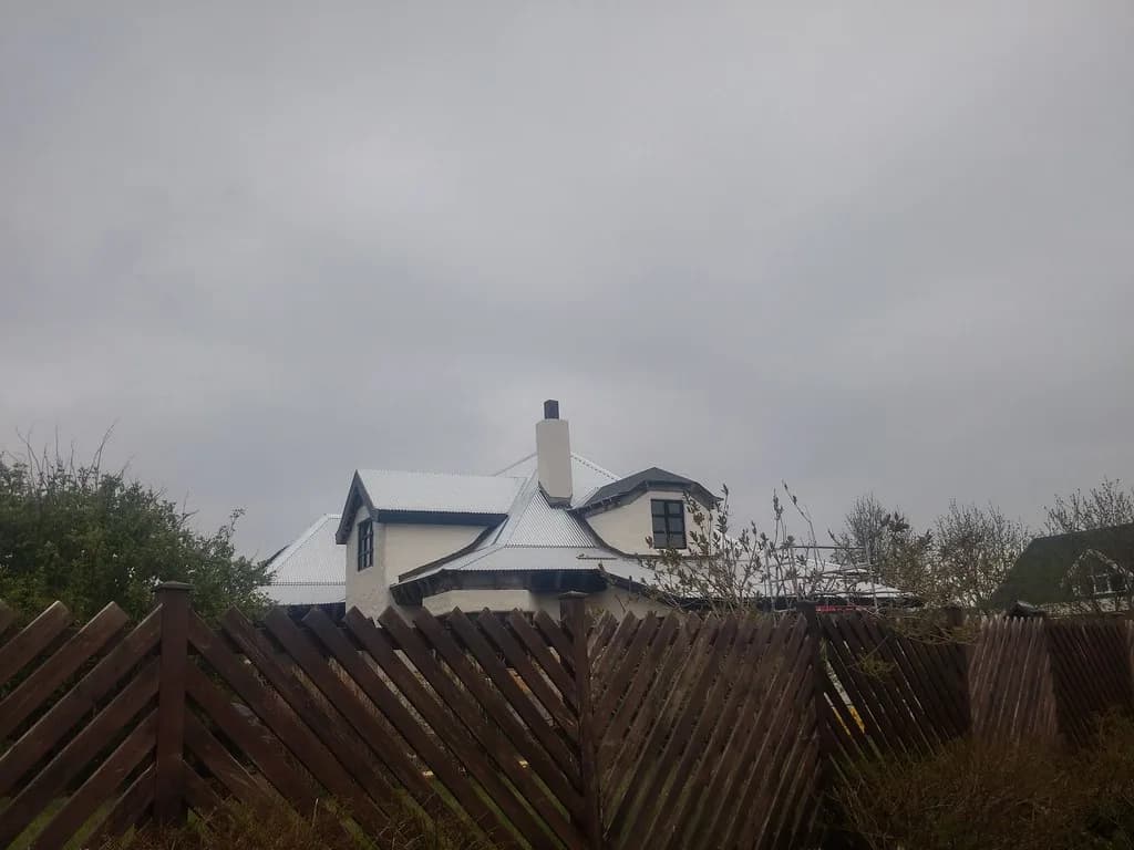 Einbýlishús með kvistum og ljósu þaki, séð úr garði.