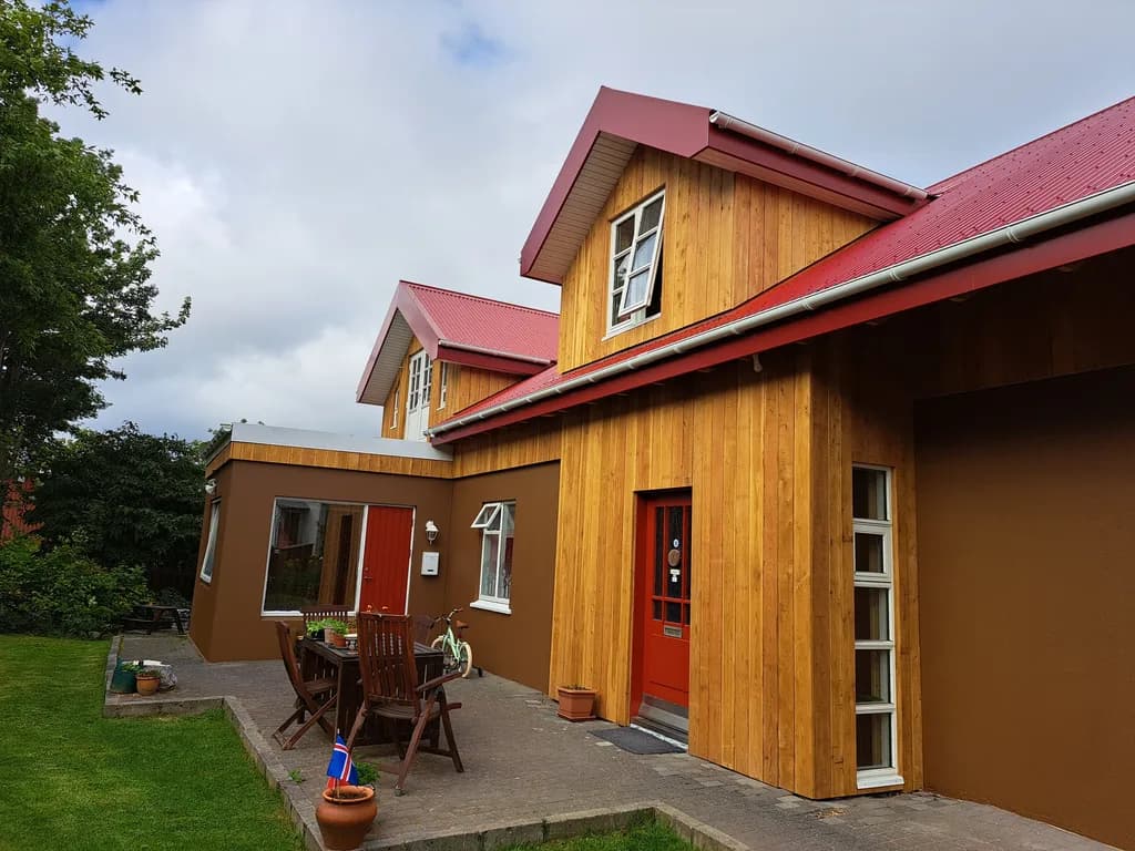 Gult timburhús með rauðu þaki og nýjum gluggakvistum.