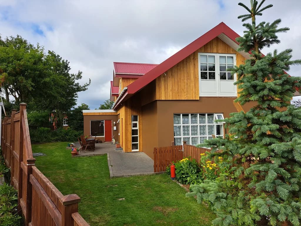 Gult timburhús með stórum gaflgluggum og rauðu þaki.