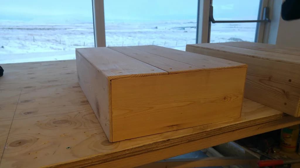 Viðarkassi á vinnuborði við glugga.