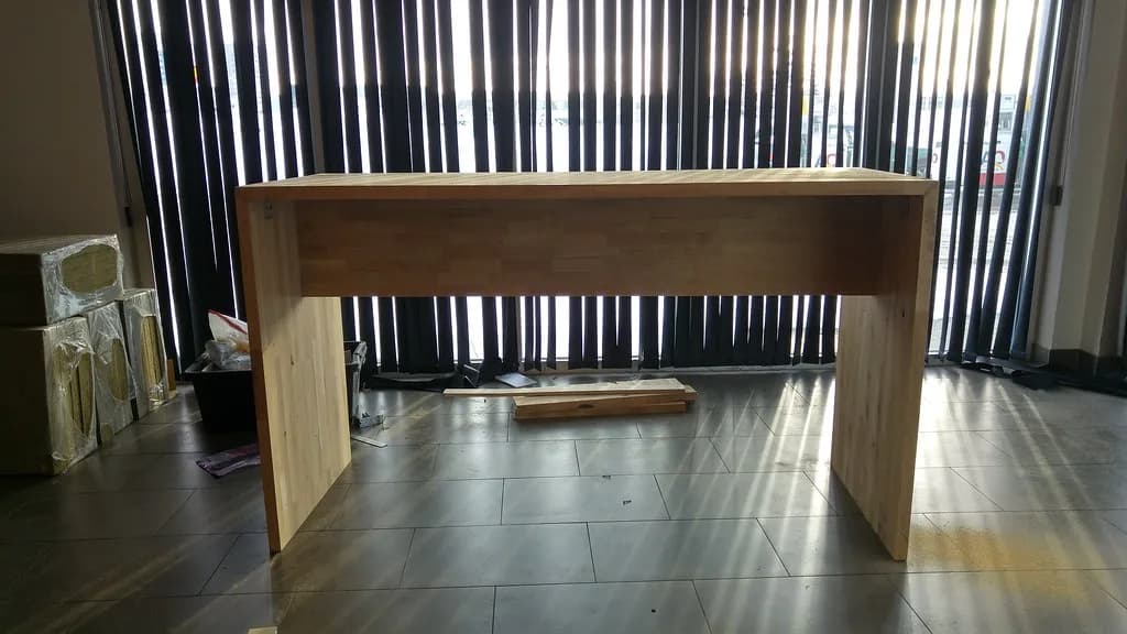 Viðarklætt borð við stóra glugga.