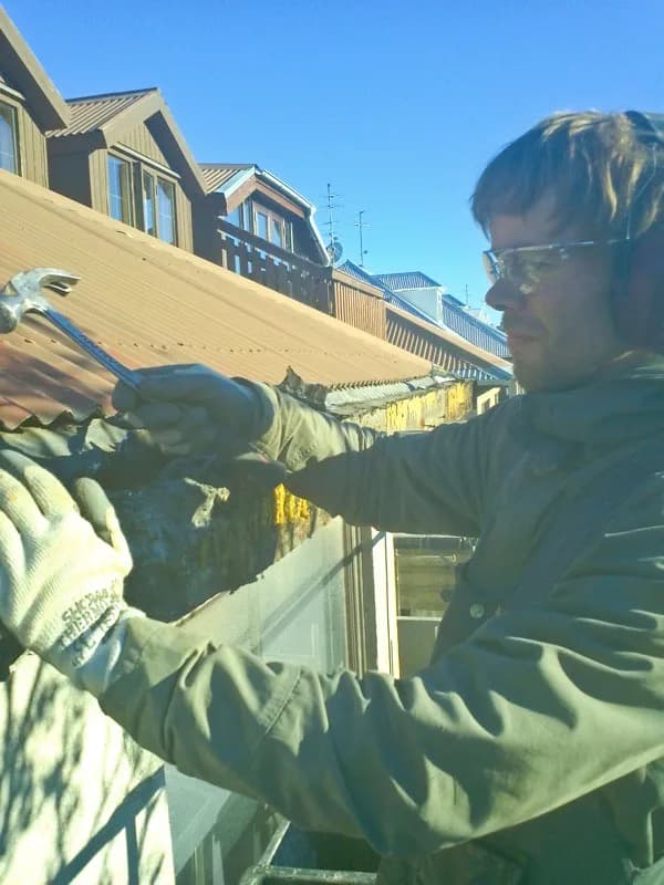 Smiður fjarlægir gamalt efni úr þakkanti.