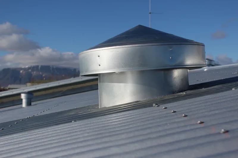 Nærmynd af málmhlíf á loftunartúðu á báruþaki.