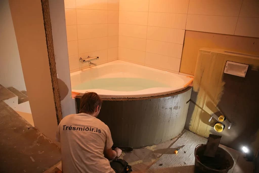 Smiður vinnur við frágang á hornbaðkari.