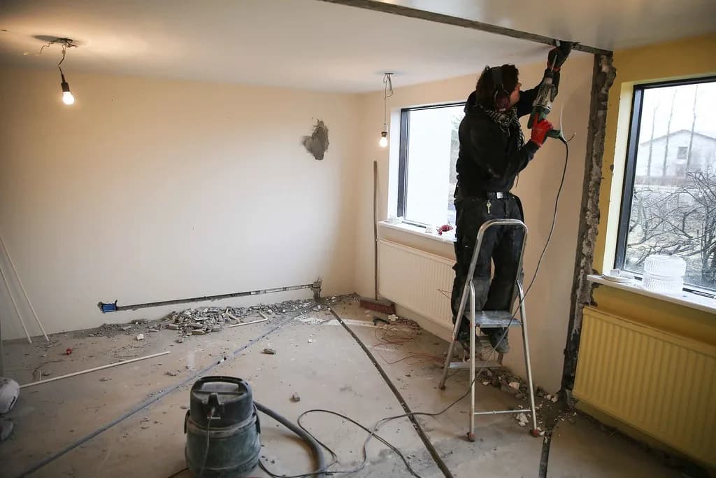Smiður í stiga vinnur við loftfrágang í rými í endurbótum.