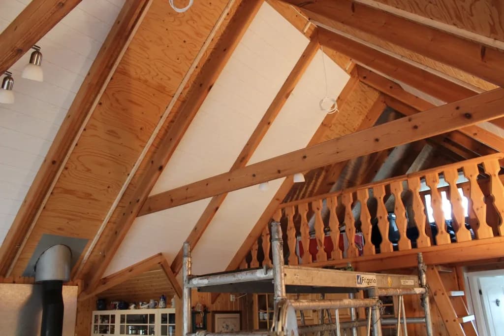 Hvít loftaklæðning í vinnslu við timburhandrið svefnlofts.