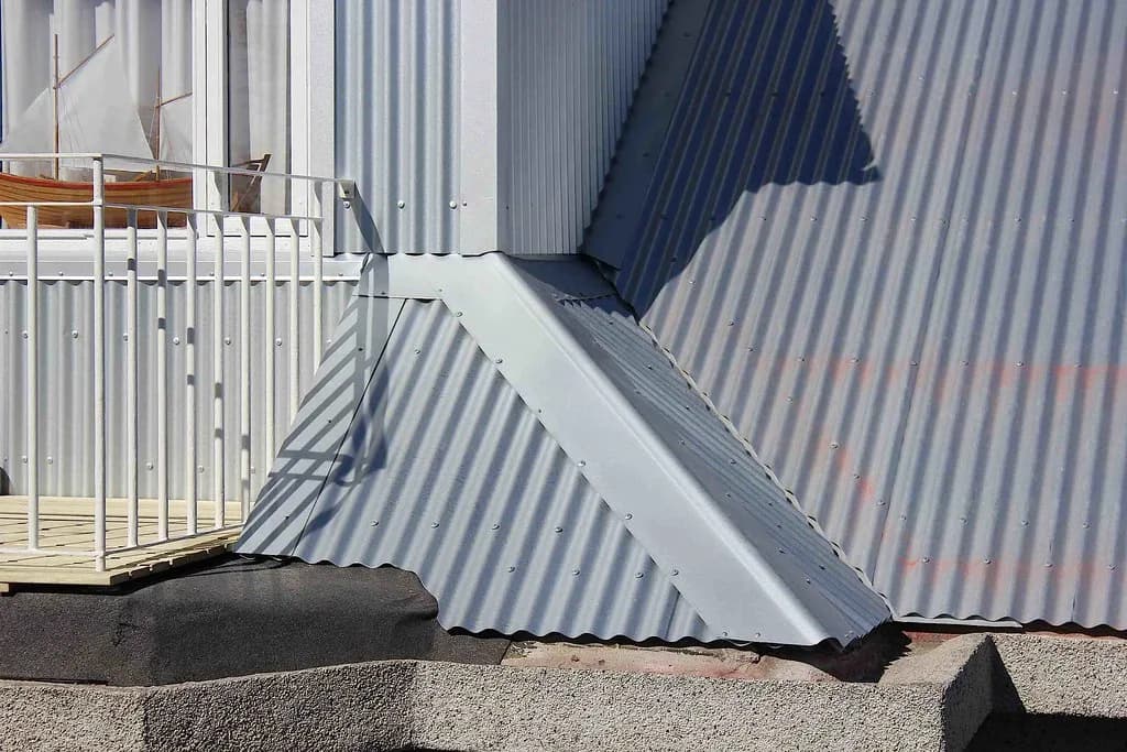 Ljós málmflasning þar sem kvistur mætir báruþaki.