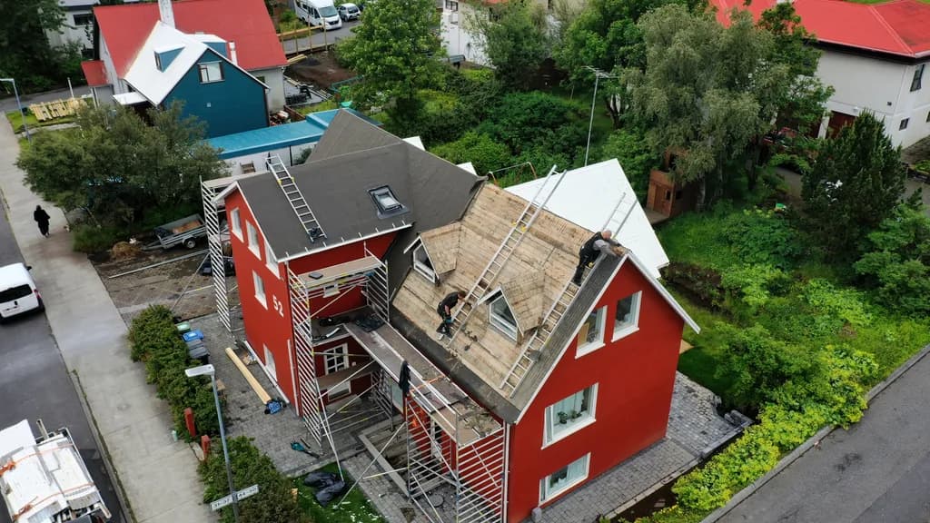 Loftmynd af rauðu húsi með opnu timburþaki og vinnupöllum.