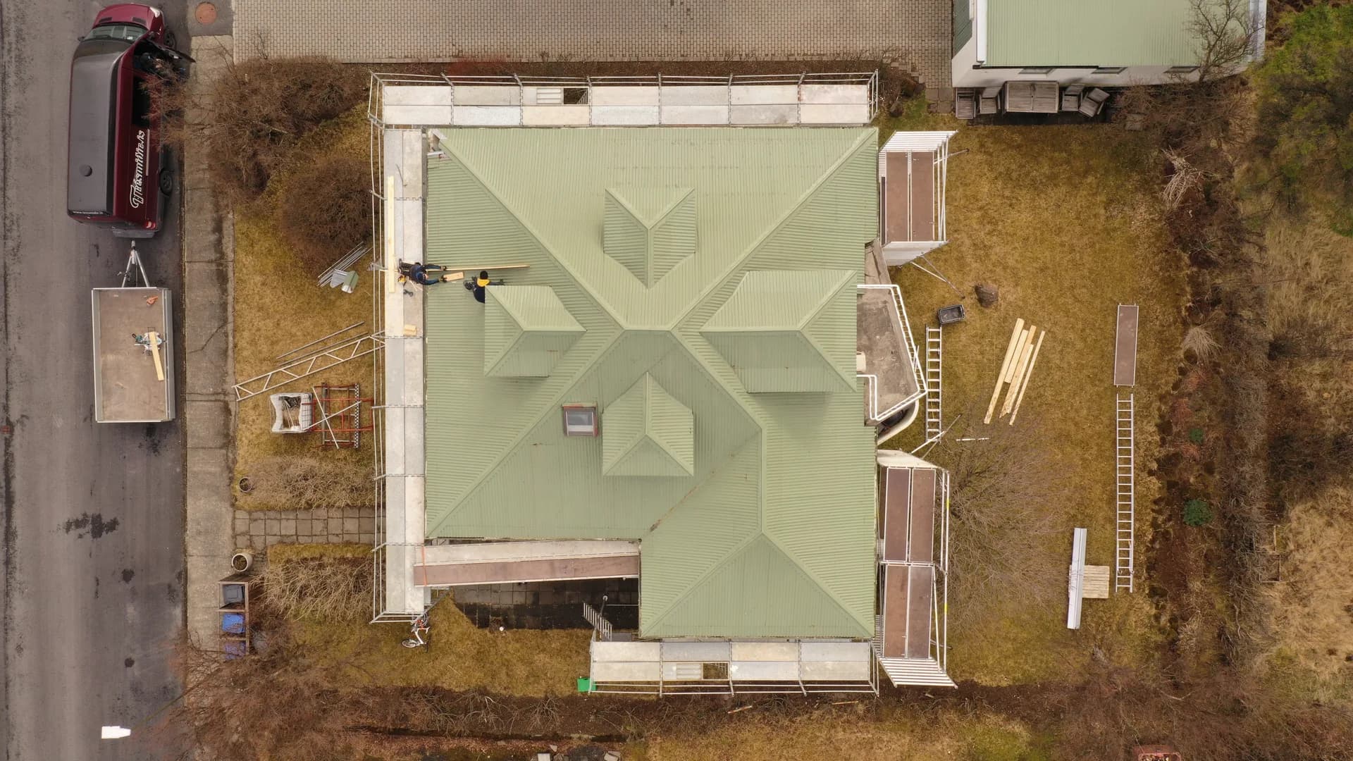 Loftmynd af grænu þaki með kvistum og vinnupöllum umhverfis húsið.