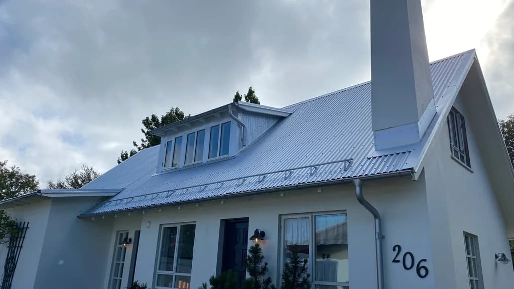 Báruð þakklæðning á húsi með kvisti og háum skorsteini.