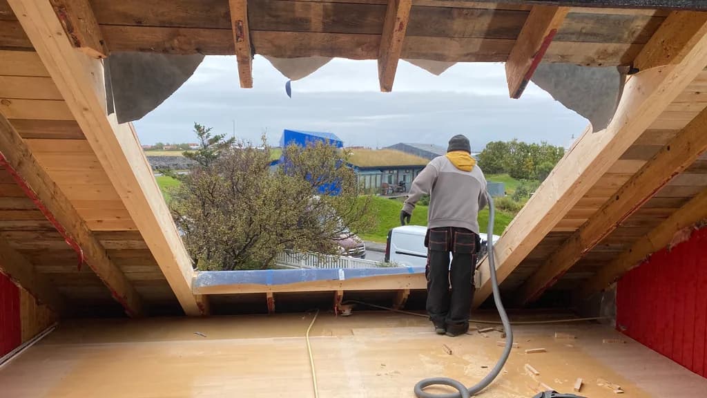Smiður við stóran gaflglugga í opnu risrými.
