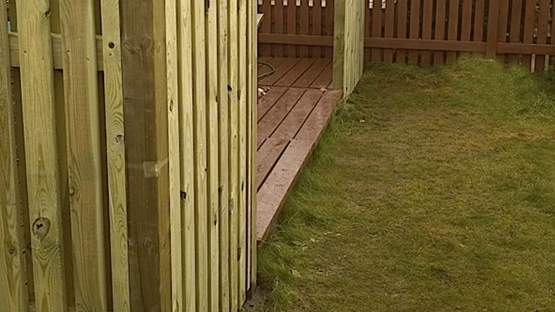 Nærmynd af timburskjólvegg við pall og grasflöt.